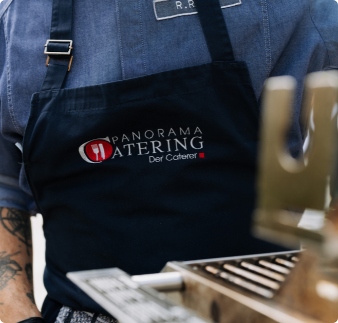 Mitarbeitende Person von Panorama Catering in Arbeitskleidung am Kücheneinsatz.“